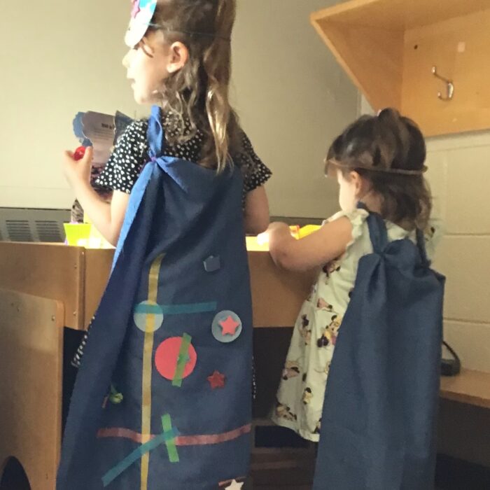 Two Sister Guardians wearing cape and masks while playing